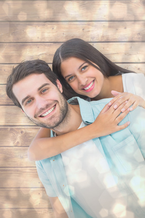 Happy casual man giving pretty girlfriend piggy back against light glowing dots design patternの写真素材