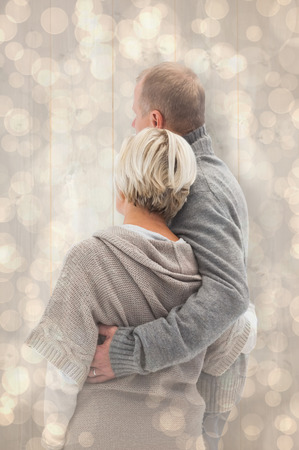 Happy mature couple in winter clothes against light glowing dots design patternの写真素材