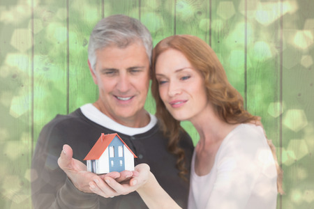 Casual couple holding small house against light glowing dots design patternの写真素材
