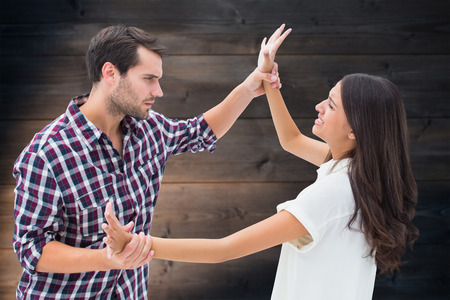 Fearful brunette being overpowered by boyfriend against wooden planks backgroundの写真素材