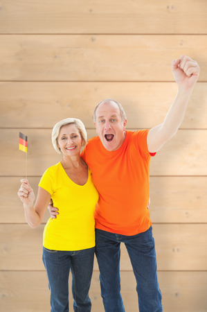 Happy german couple cheering at camera against wooden planksの写真素材