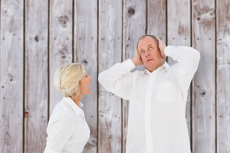 Angry older couple arguing with each other against wooden planksの写真素材