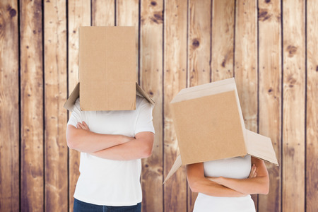 Mature couple wearing boxes over their heads against wooden planksの写真素材