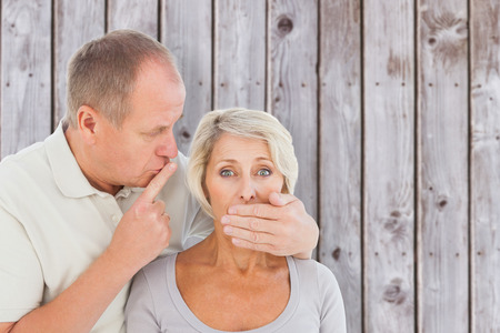 Man silencing his fearful partner against wooden planksの写真素材