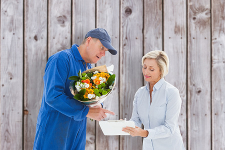 Happy flower delivery man with customer against wooden planksの写真素材