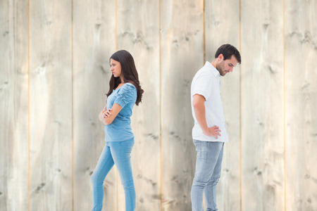 Upset couple not talking to each other after fight against pale wooden planksの写真素材