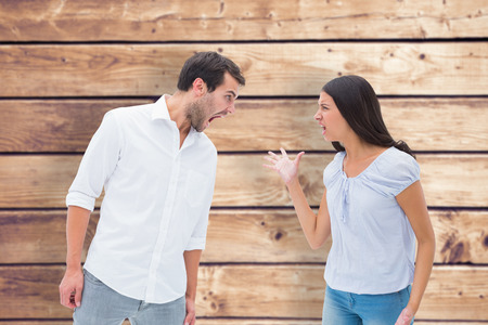 Angry couple shouting at each other against wooden planks backgroundの写真素材