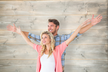 Attractive young couple standing with hands out against bleached wooden planks backgroundの写真素材