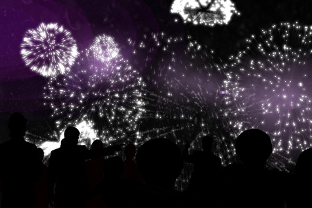 Silhouette of cheering people against white fireworks exploding on black backgroundの写真素材