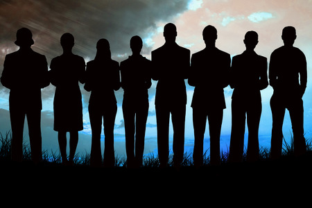 Silhouette of business people in a row against blue sky over grass