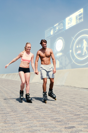Fit couple rollerblading on the promenade  against fitness interfaceの写真素材