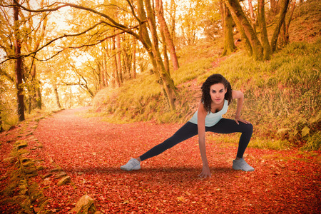 Fit woman stretching her legs against peaceful autumn scene in forestの写真素材