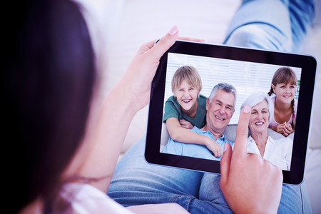 Composite image of grandchildren and grandparents sitting on couchの写真素材