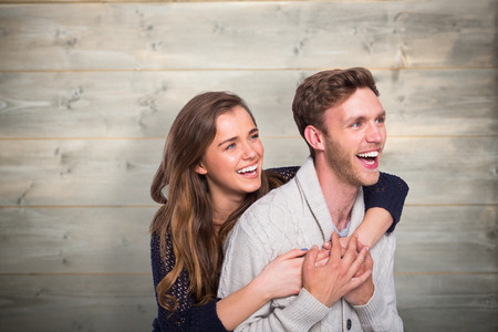 Cheerful young couple embracing against bleached wooden planks backgroundの写真素材
