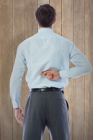 Businessman crossing fingers behind his back against wooden surface with planksの写真素材