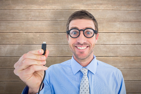 Geeky businessman holding a cable against wooden surface with planks
