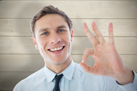 Businessman showing ok sign against bleached wooden planks backgroundの写真素材