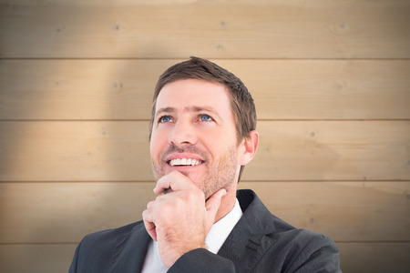 Businessman smiling and thinking against bleached wooden planks backgroundの写真素材