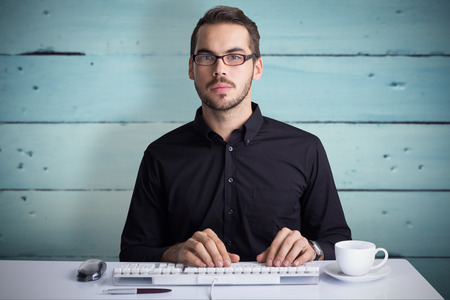 Focused businessman typing on keyboard  against painted blue wooden planks