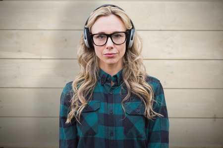 Pretty blonde listening to music against bleached wooden planks background