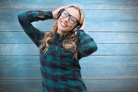 Pretty blonde listening to music against wooden planks