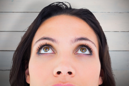 Pretty brunette looking up thoughfully against painted blue wooden planks