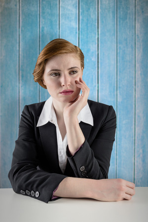 Thinking redhead businesswoman against wooden planksの写真素材
