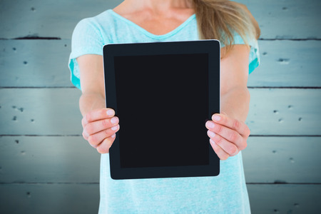 Mid section of woman showing a tablet pc against painted blue wooden planksの写真素材