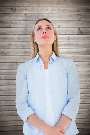 Portrait of blonde woman posing and looking up against wooden planks backgroundの写真素材