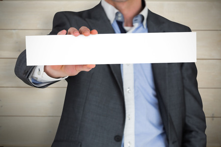 Businessman in grey suit showing card against bleached wooden planks backgroundの写真素材
