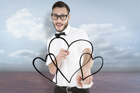 Geeky hipster pointing at camera against clouds in a roomの写真素材