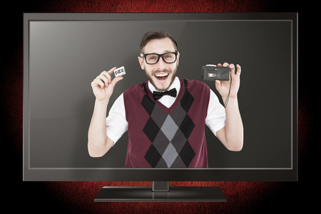Geeky hipster holding a retro tape cassette player against red background with vignette