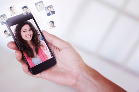 Womans hand holding black smartphone against smiling woman with creative team working behindの写真素材