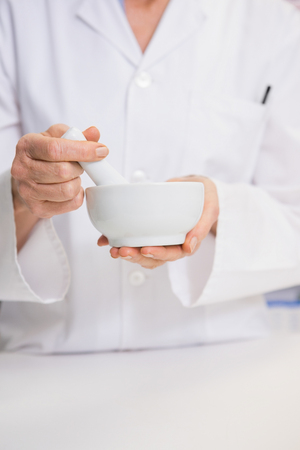 Mid section of pharmacist mixing a medicine in the pharmacyの写真素材