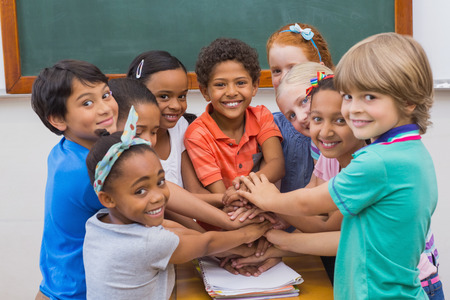 Cute pupils smiling at camera in classroom at the elementary school