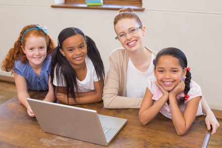 Teacher and pupils looking at laptop at the elementary schoolの写真素材