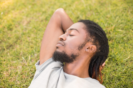 Handsome hipster relaxing in the park on a sunny dayの写真素材
