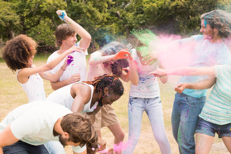 Happy friends throwing powder paint on a sunny dayの写真素材