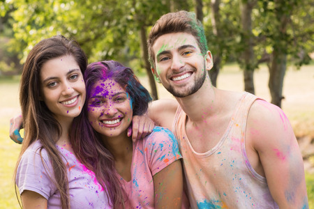 Happy friends covered in powder paint on a sunny day