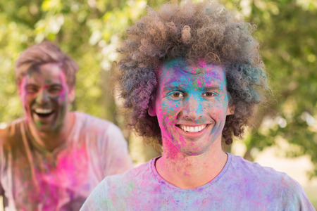 Happy friends covered in powder paint on a sunny dayの写真素材