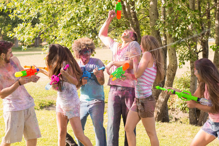 Happy friends covered in powder paint on a sunny day