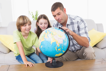 Father and children exploring globe in living roomの写真素材