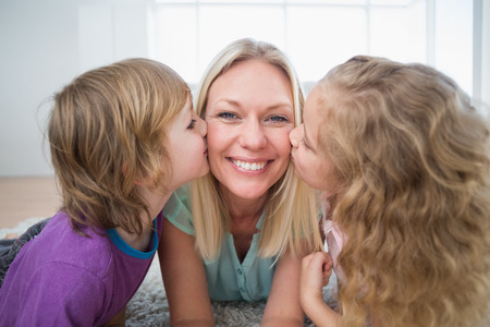 Portrait of happy woman being kissed by children at homeの写真素材