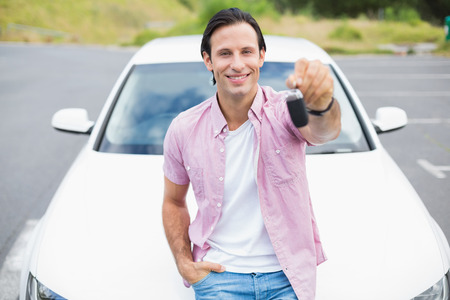 Man smiling and showing key outside his carの写真素材