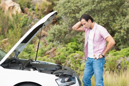 Stressed man looking at engine of his car