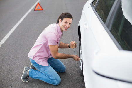 Man changing wheel after a car breakdown at the side of the roadの写真素材