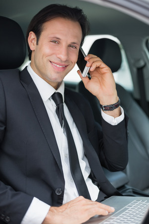 Businessman working in the drivers seat in his carの写真素材
