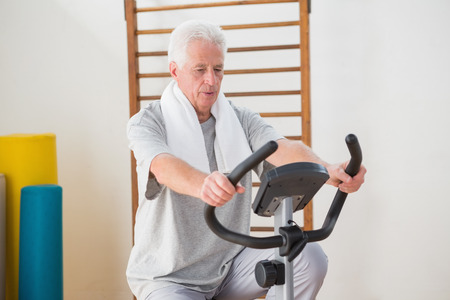 Senior man doing exercise bike in fitness studioの写真素材