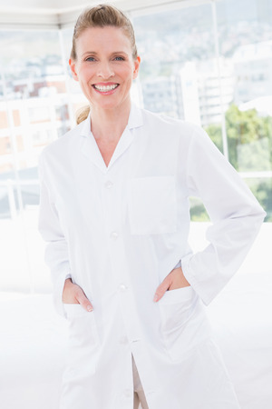 Smiling doctor looking at camera with hands in pockets in medical officeの写真素材