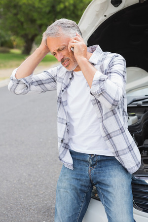 Stressed man calling beside his broken down carの写真素材